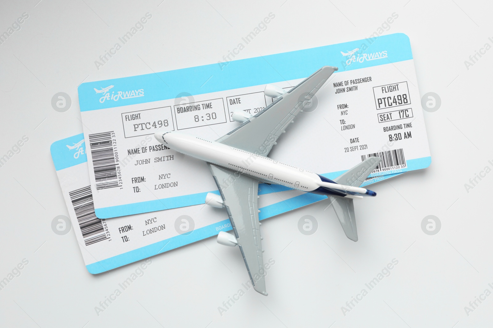 Photo of Travel agency. Flight tickets and plane model on light background, top view