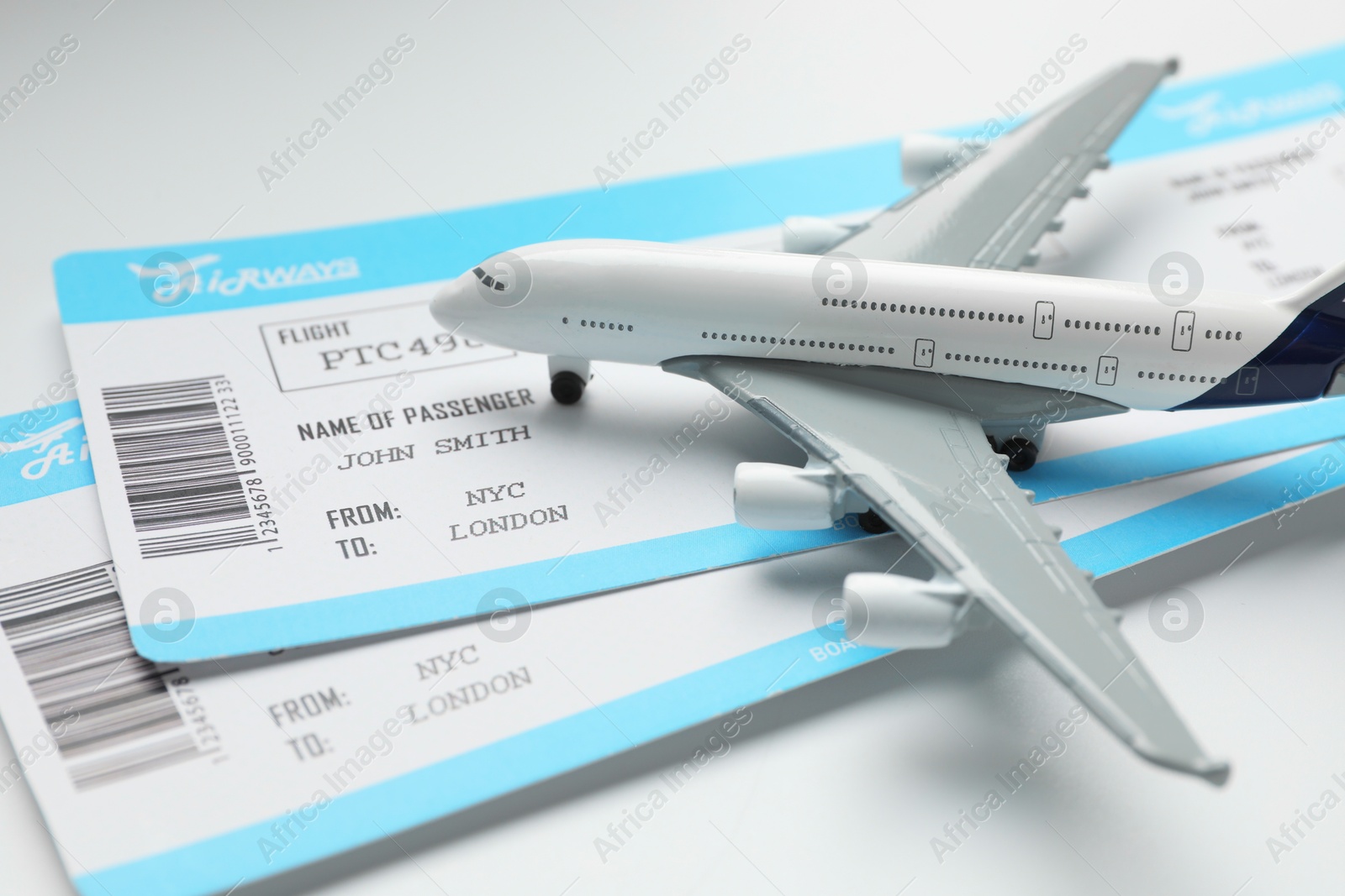 Photo of Travel agency. Flight tickets and plane model on light background, closeup