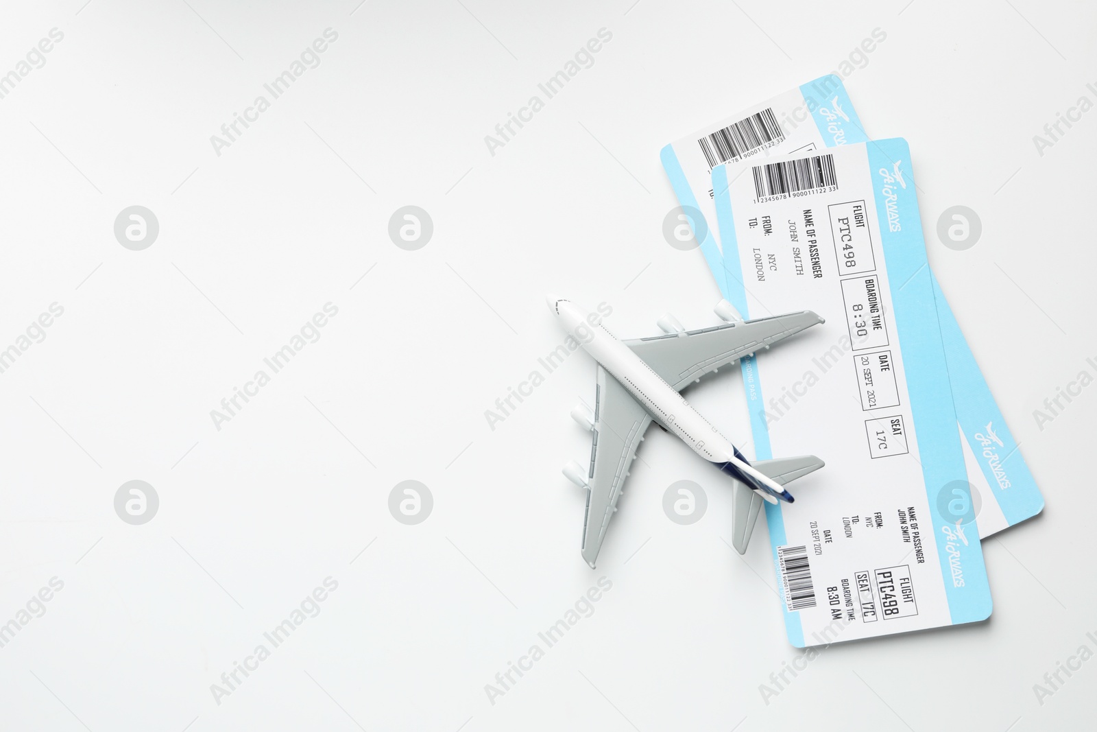 Photo of Travel agency. Flight tickets and plane model on light background, flat lay. Space for text