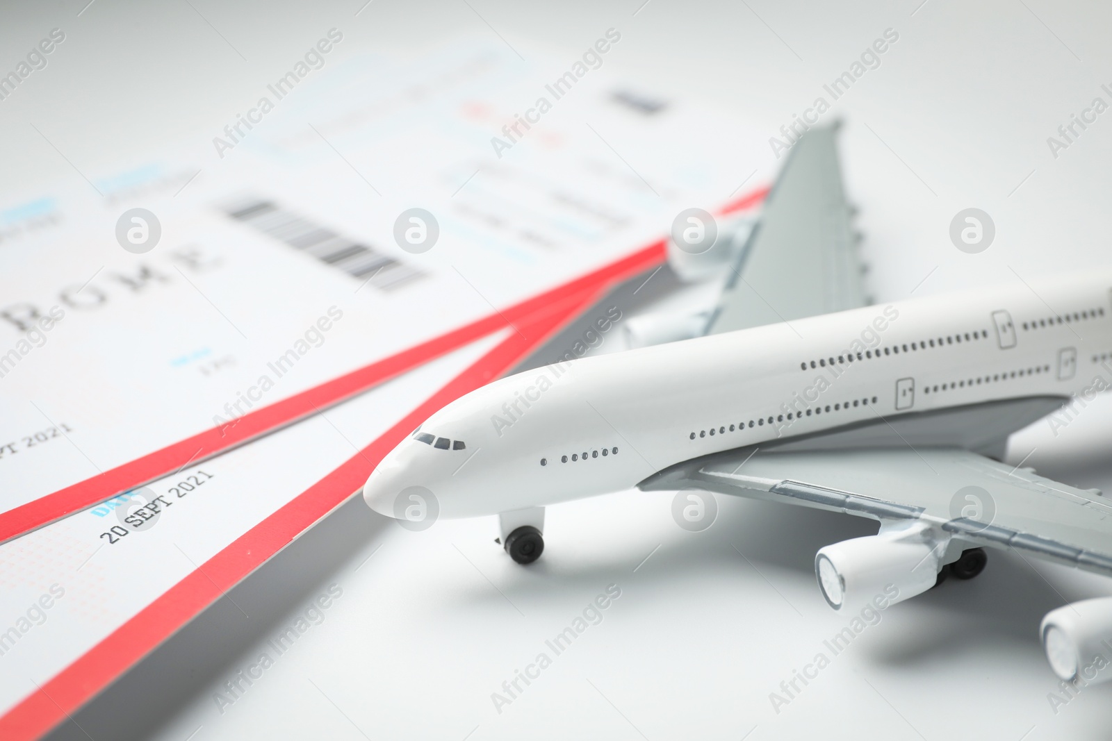 Photo of Travel agency. Flight tickets and plane model on light background, closeup