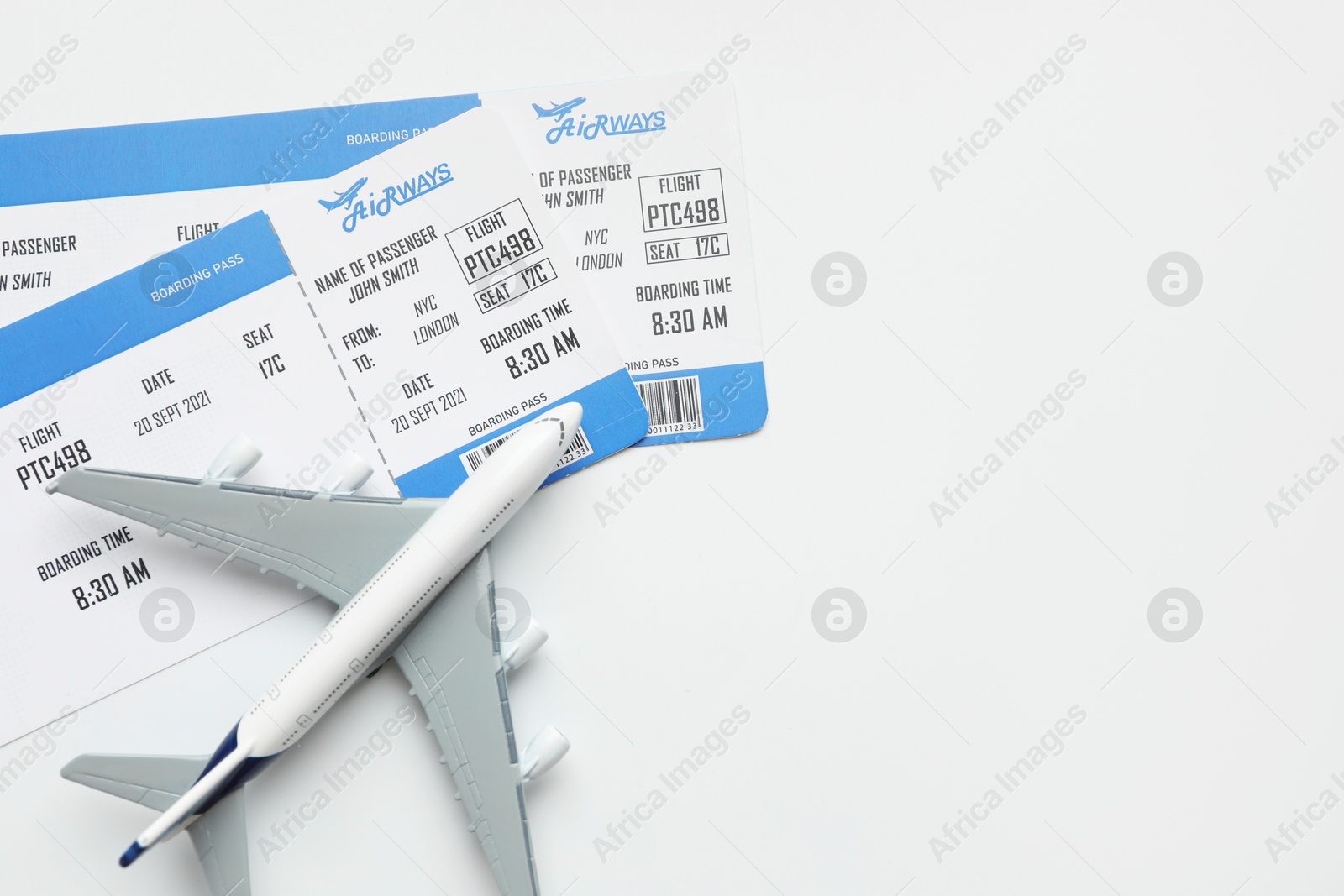 Photo of Travel agency. Flight tickets and plane model on light background, flat lay. Space for text