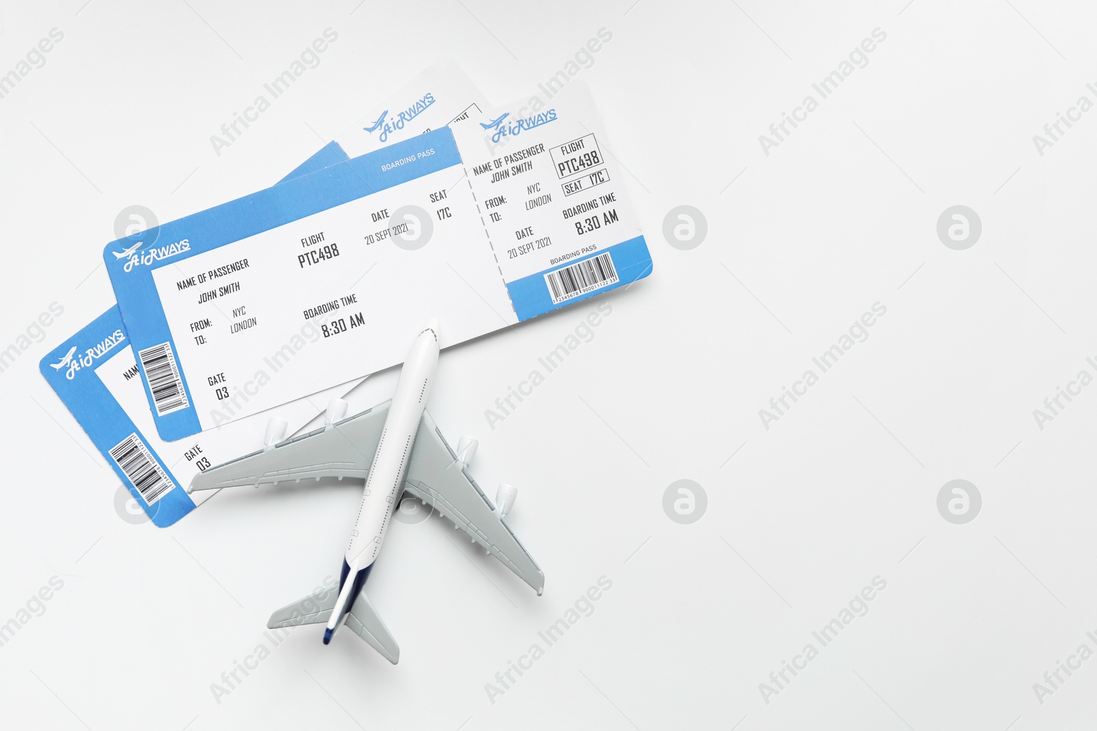 Photo of Travel agency. Flight tickets and plane model on light background, flat lay. Space for text