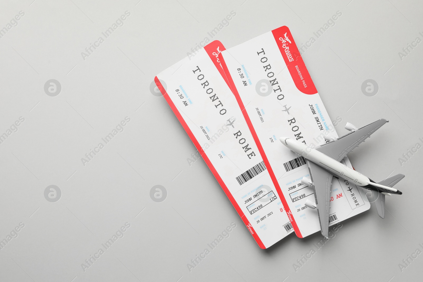 Photo of Travel agency. Flight tickets and plane model on grey background, flat lay. Space for text