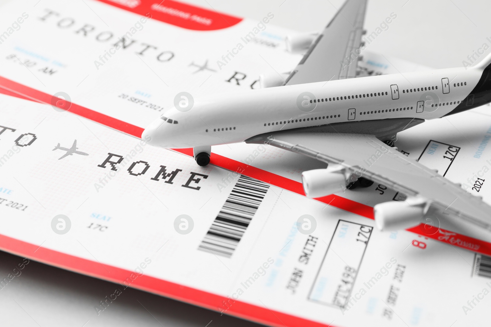 Photo of Travel agency. Flight tickets and plane model on grey background, closeup