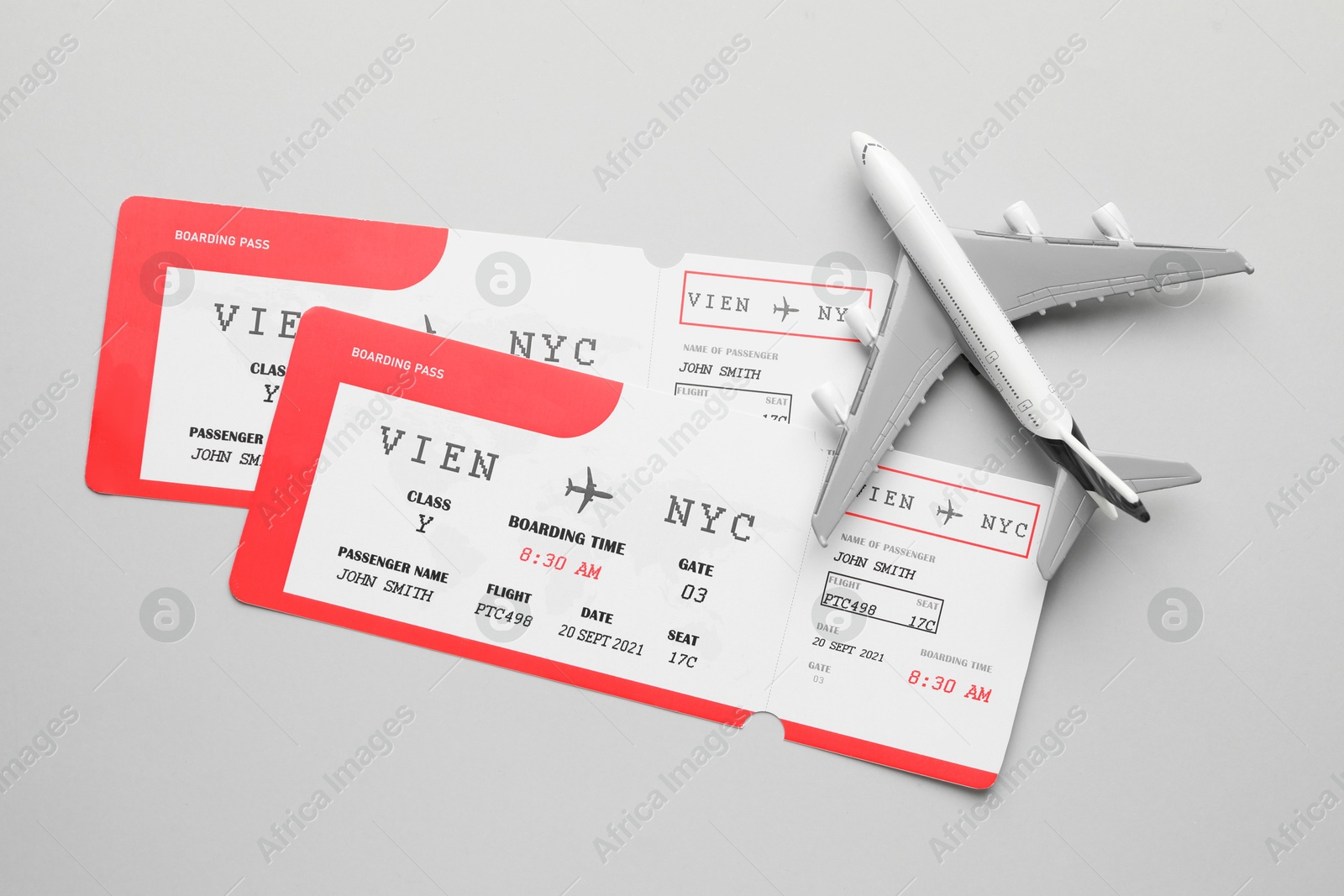 Photo of Travel agency. Flight tickets and plane model on grey background, flat lay