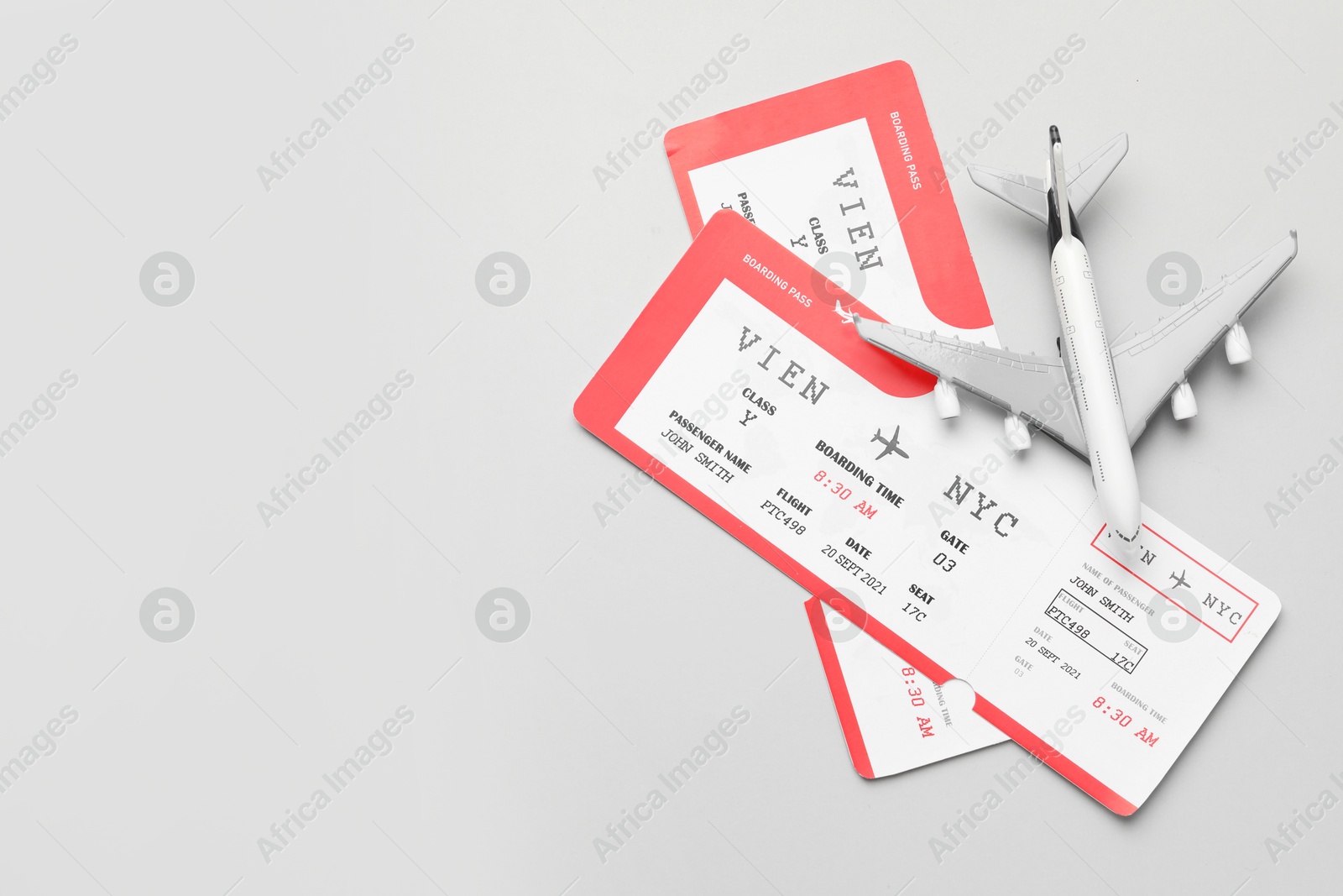 Photo of Travel agency. Flight tickets and plane model on grey background, flat lay. Space for text