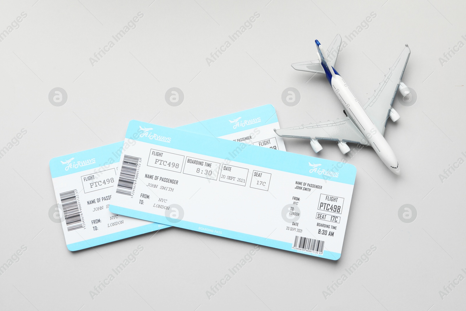 Photo of Travel agency. Flight tickets and plane model on grey background, flat lay