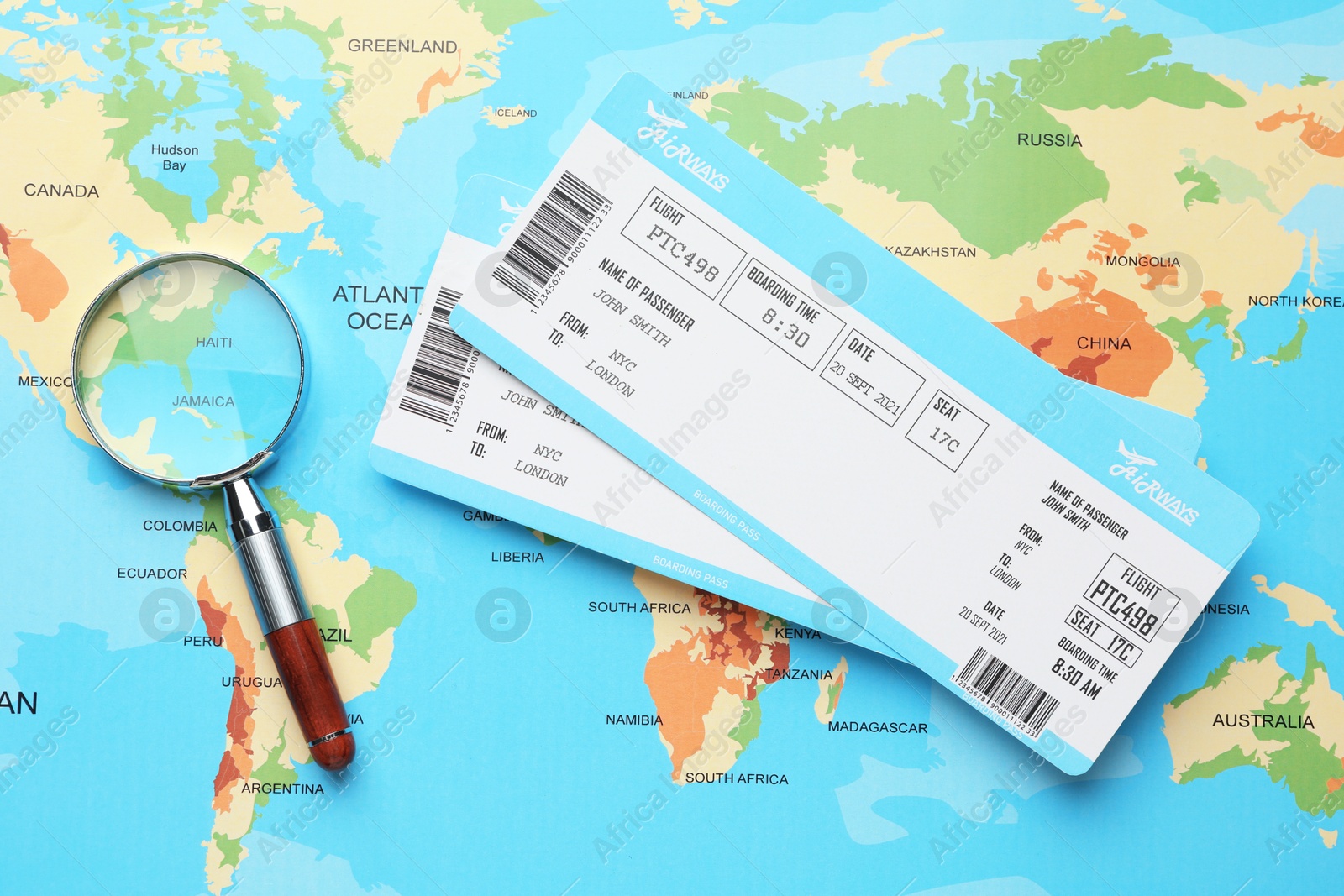 Photo of Travel agency. Flight tickets and magnifying glass on world map, flat lay