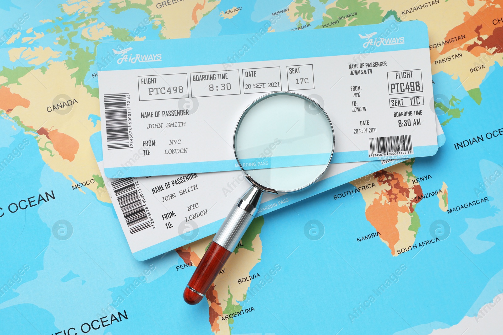 Photo of Travel agency. Flight tickets and magnifying glass on world map, flat lay