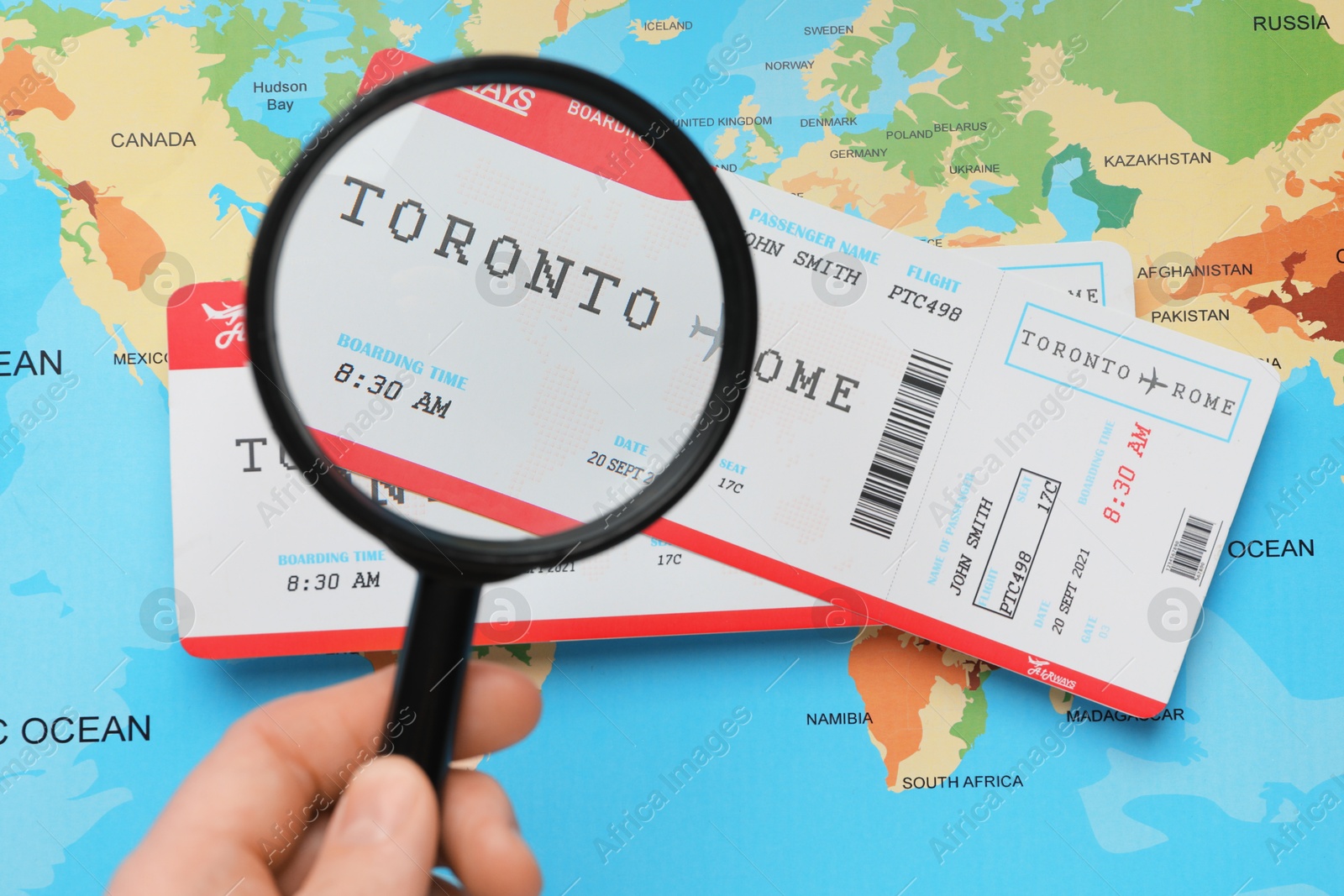 Photo of Travel agency. Man looking at flight tickets through magnifying glass at world map, top view