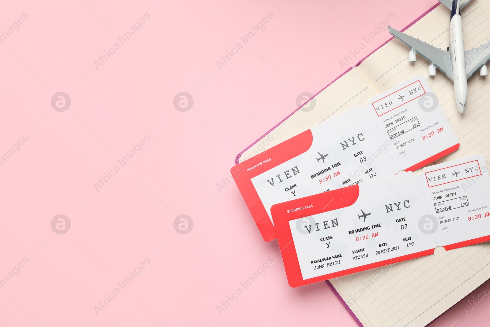 Photo of Travel agency. Flight tickets, plane model and open notebook on pink background, top view. Space for text