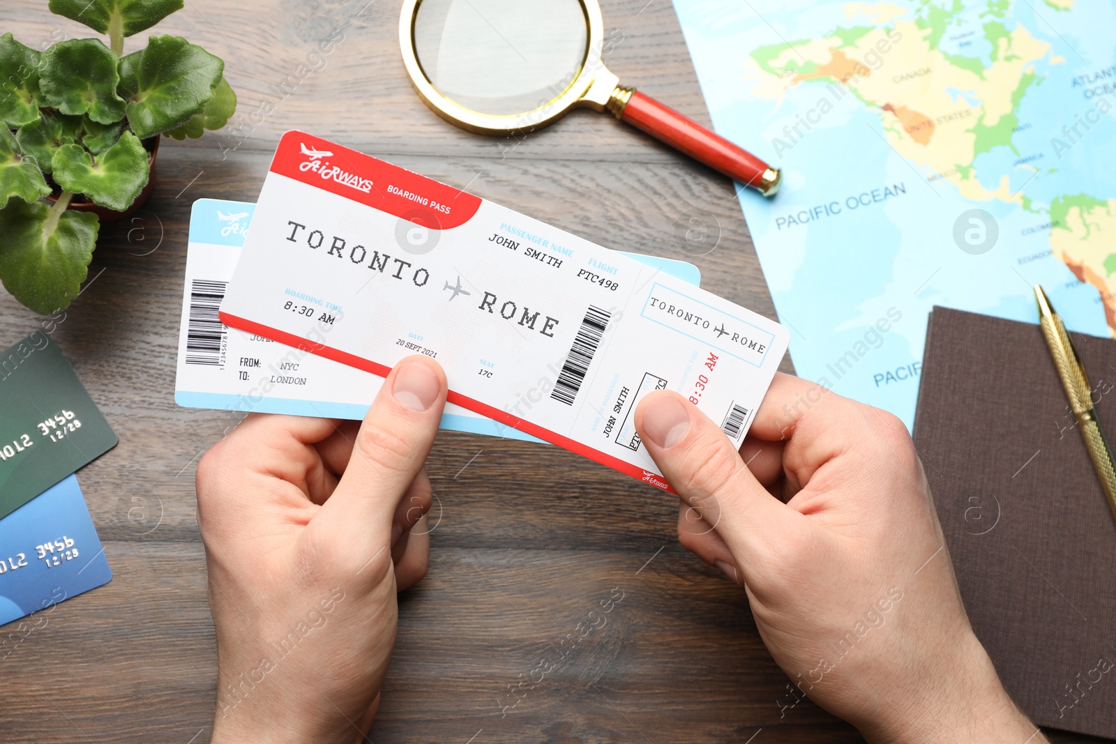 Photo of Travel agency. Man with flight tickets at wooden table, top view