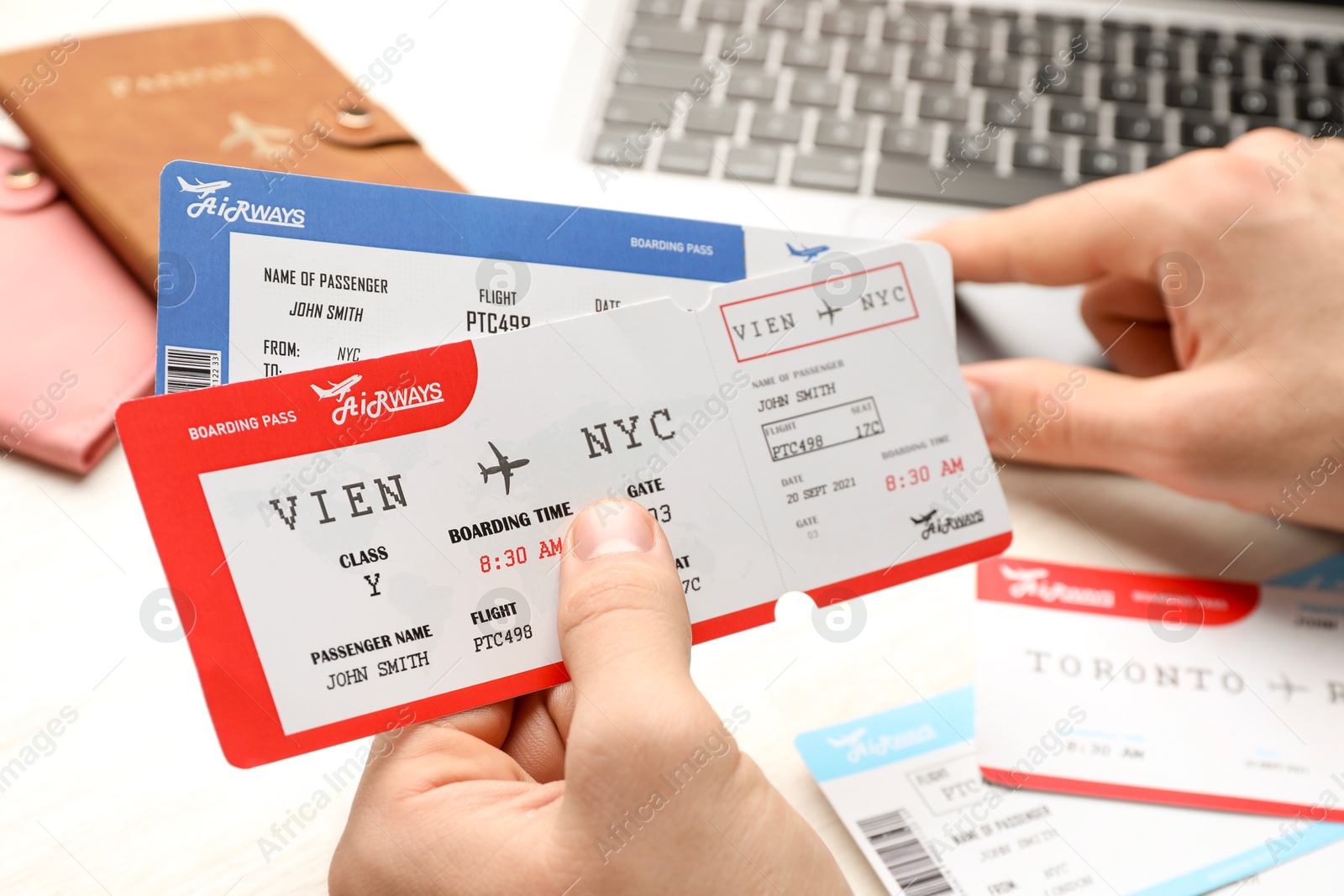 Photo of Travel agency. Man with flight tickets using laptop at light table, closeup