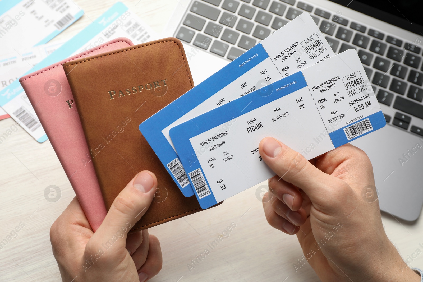 Photo of Travel agency. Man with flight tickets and passports at light wooden table, closeup