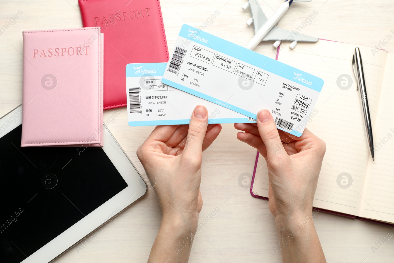 Photo of Travel agency. Woman with flight tickets at light wooden table, top view