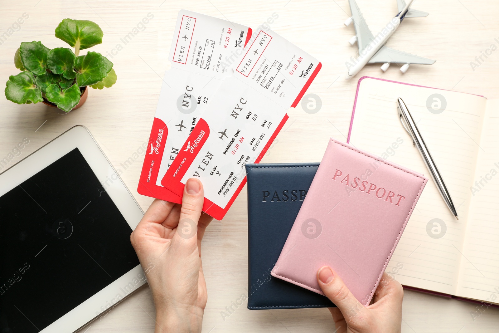 Photo of Travel agency. Woman with flight tickets and passports at light wooden table, top view