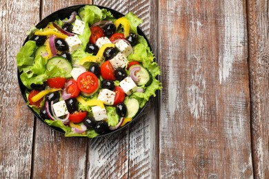 Photo of Delicious fresh Greek salad on wooden table, top view. Space for text