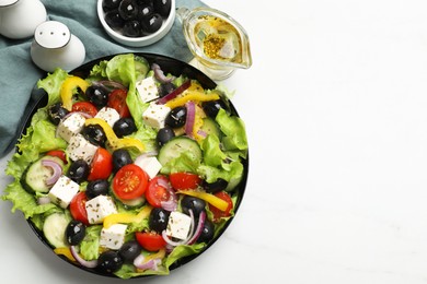 Photo of Delicious fresh Greek salad and ingredients on white table, flat lay. Space for text