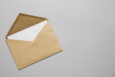 Kraft paper envelope with letter on gray background, top view. Mockup for design