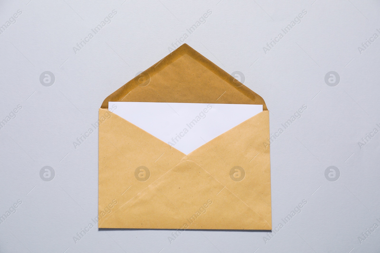 Photo of Kraft paper envelope with letter on gray background, top view. Mockup for design