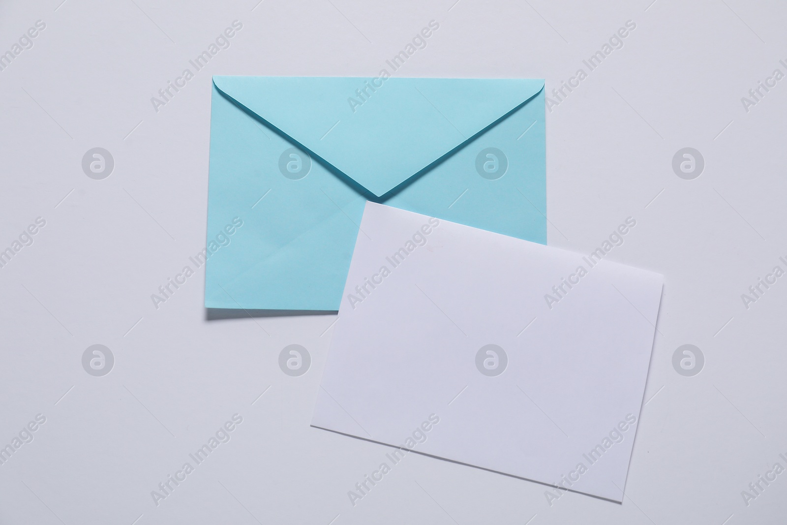 Photo of Paper envelope with letter on white background, top view. Mockup for design