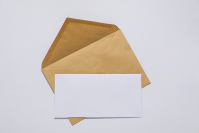 Photo of Kraft paper envelope with letter on white background, top view. Mockup for design