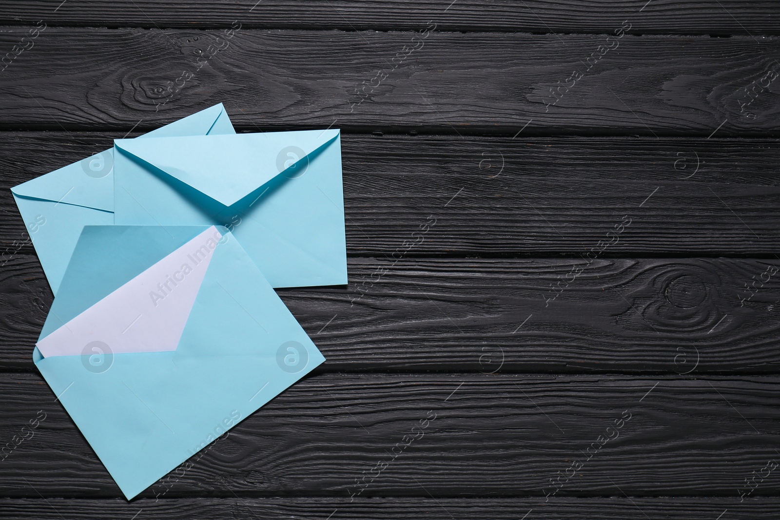 Photo of Paper envelopes with letter on black wooden background, flat lay. Mockup for design