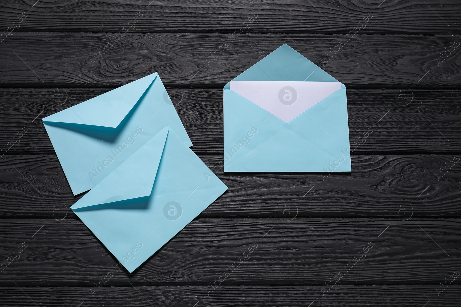 Photo of Paper envelopes with letter on black wooden background, flat lay. Mockup for design