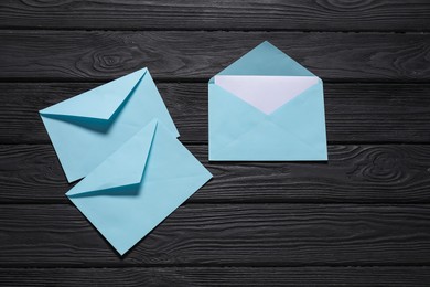 Paper envelopes with letter on black wooden background, flat lay. Mockup for design