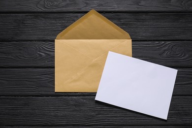 Photo of Kraft paper envelope with letter on black wooden background, top view. Mockup for design