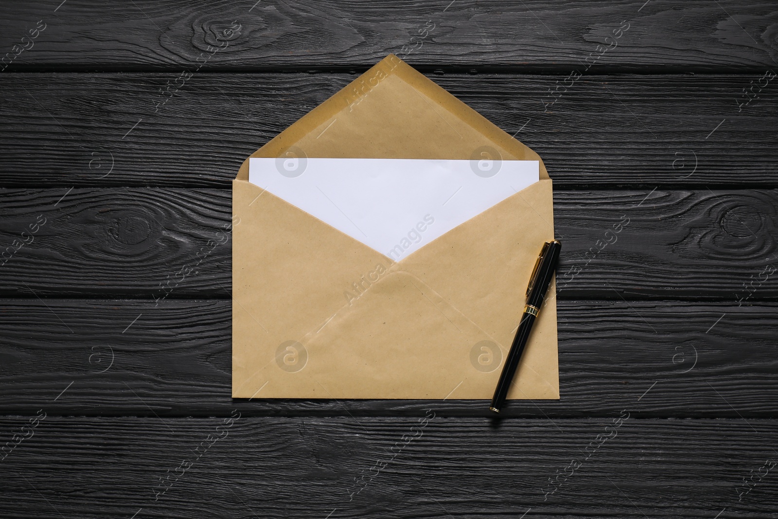 Photo of Kraft paper envelope with letter and pen on black wooden background, top view. Mockup for design