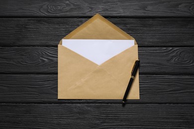 Kraft paper envelope with letter and pen on black wooden background, top view. Mockup for design