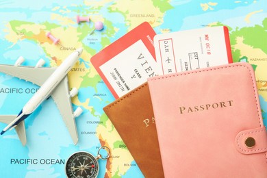 Photo of Passports with tickets, compass and plane model on world map, flat lay