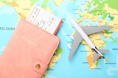 Photo of Passport with ticket and plane model on world map, flat lay