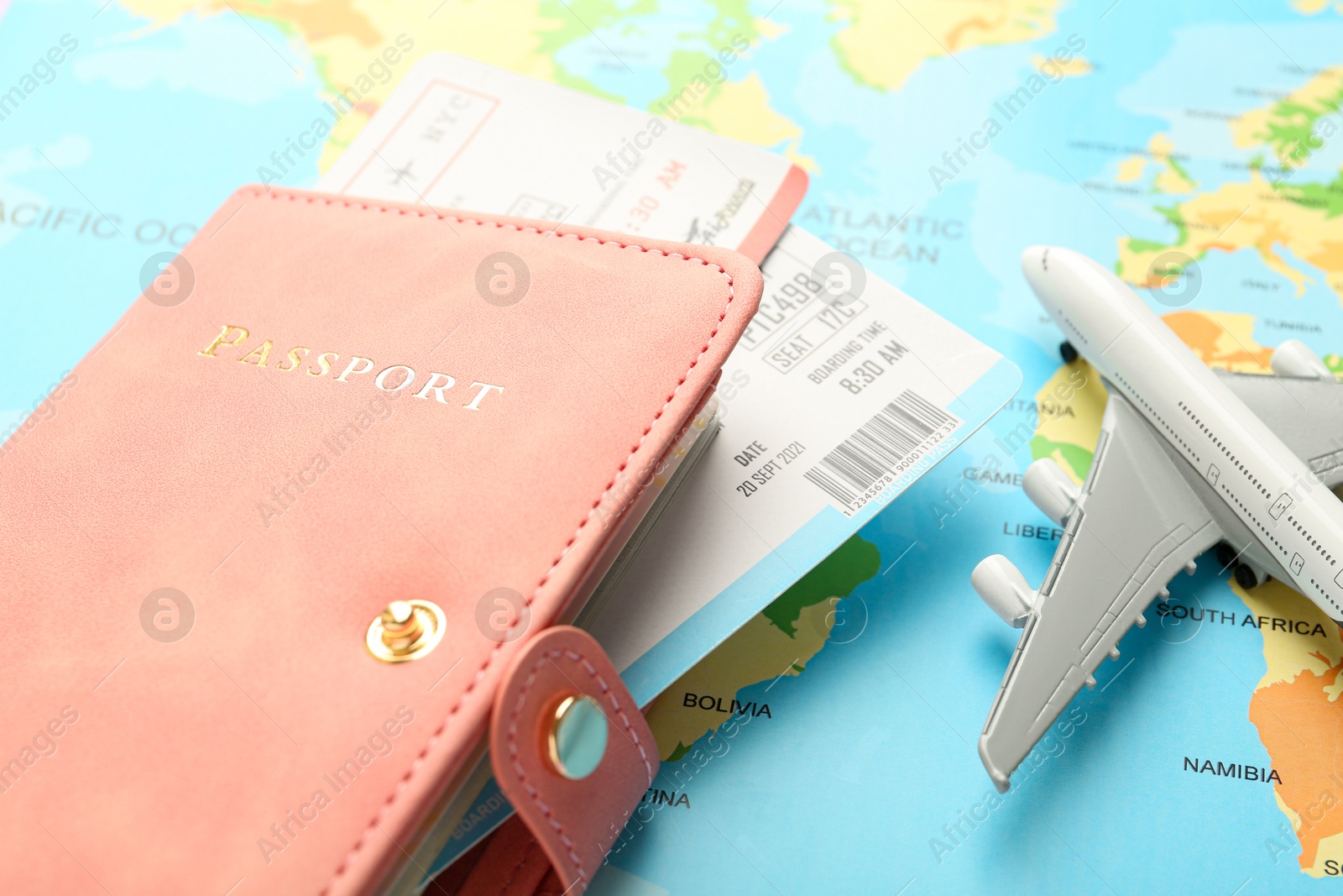 Photo of Passport with tickets and plane model on world map, closeup