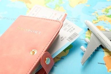 Photo of Passport with tickets and plane model on world map, closeup