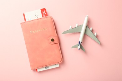 Photo of Passport with ticket and plane model on pink background, flat lay