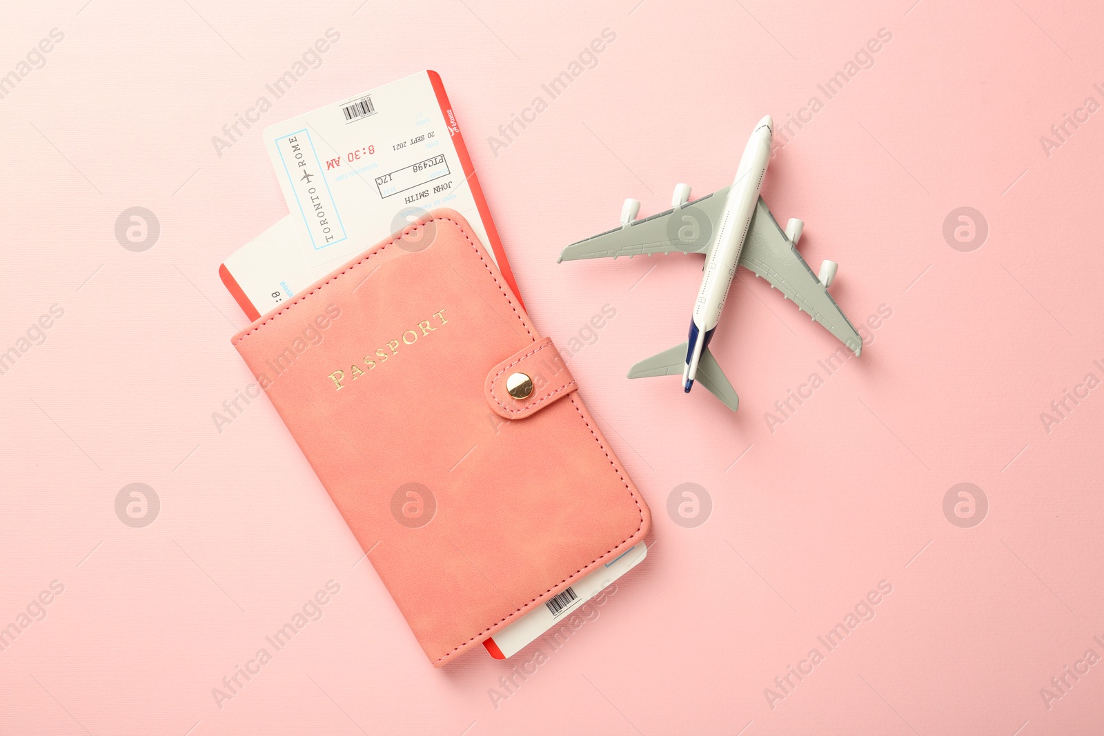 Photo of Passport with tickets and plane model on pink background, flat lay