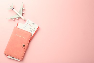 Photo of Passport with tickets and plane model on pink background, flat lay. Space for text