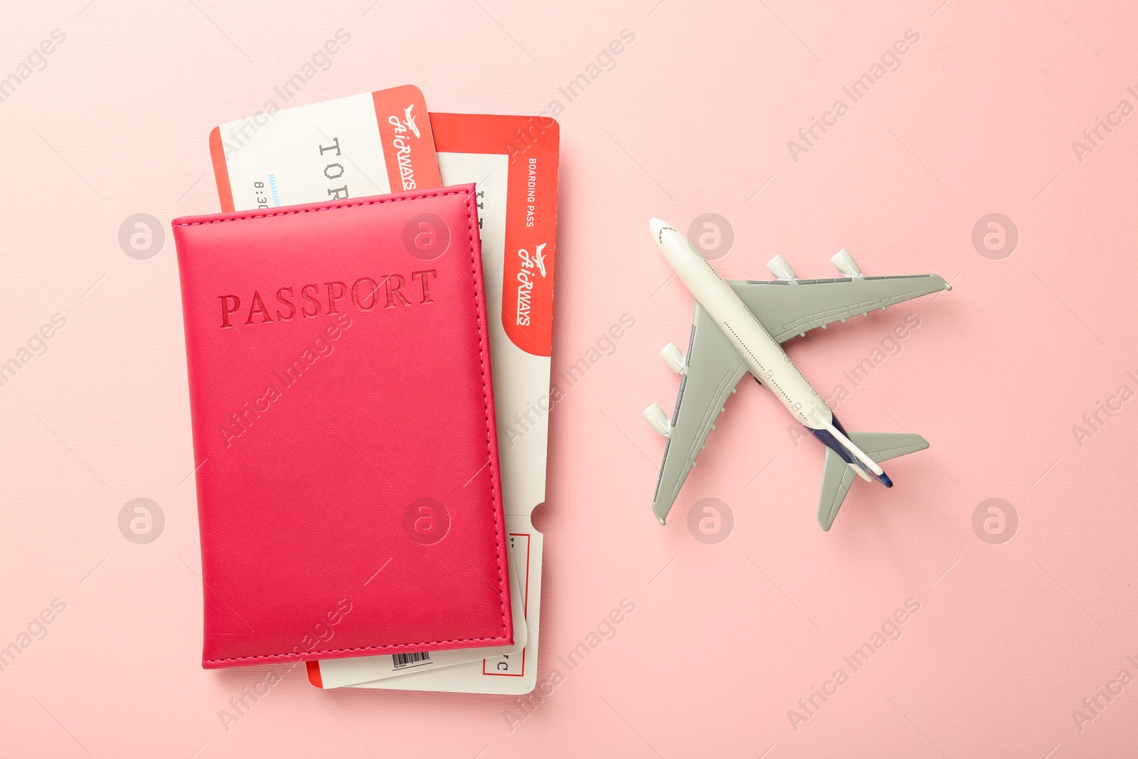 Photo of Passport with tickets and plane model on pink background, flat lay