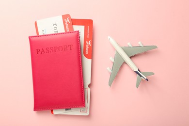 Photo of Passport with tickets and plane model on pink background, flat lay