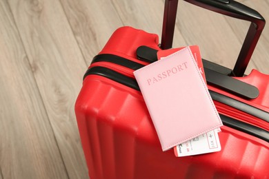 Photo of Passport with ticket and red suitcase on floor, closeup. Space for text