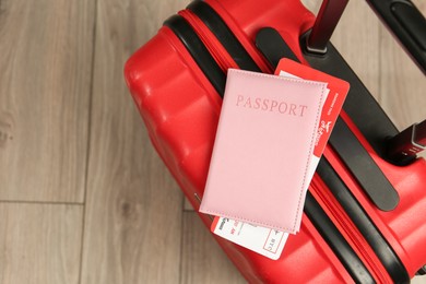 Photo of Passport with ticket and red suitcase on floor, top view. Space for text