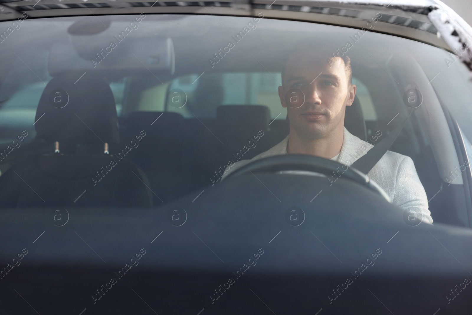 Photo of Driver behind steering wheel of modern car, view from windshield