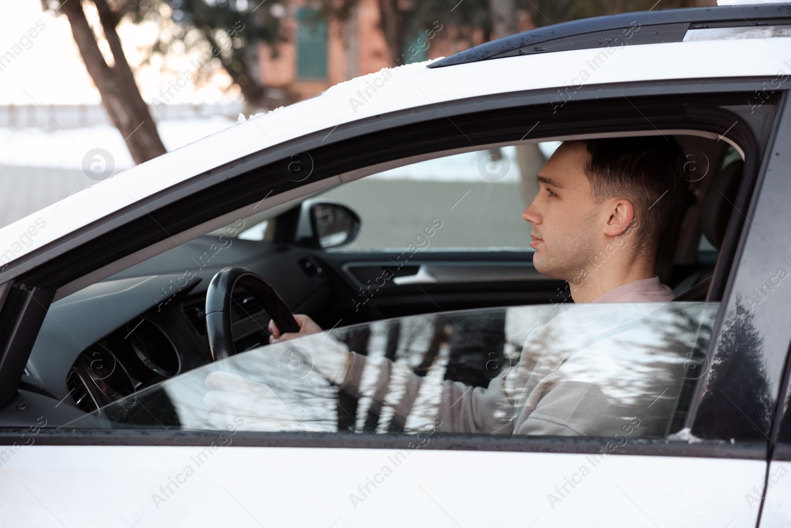 Photo of Driver behind steering wheel of modern car, view from outside