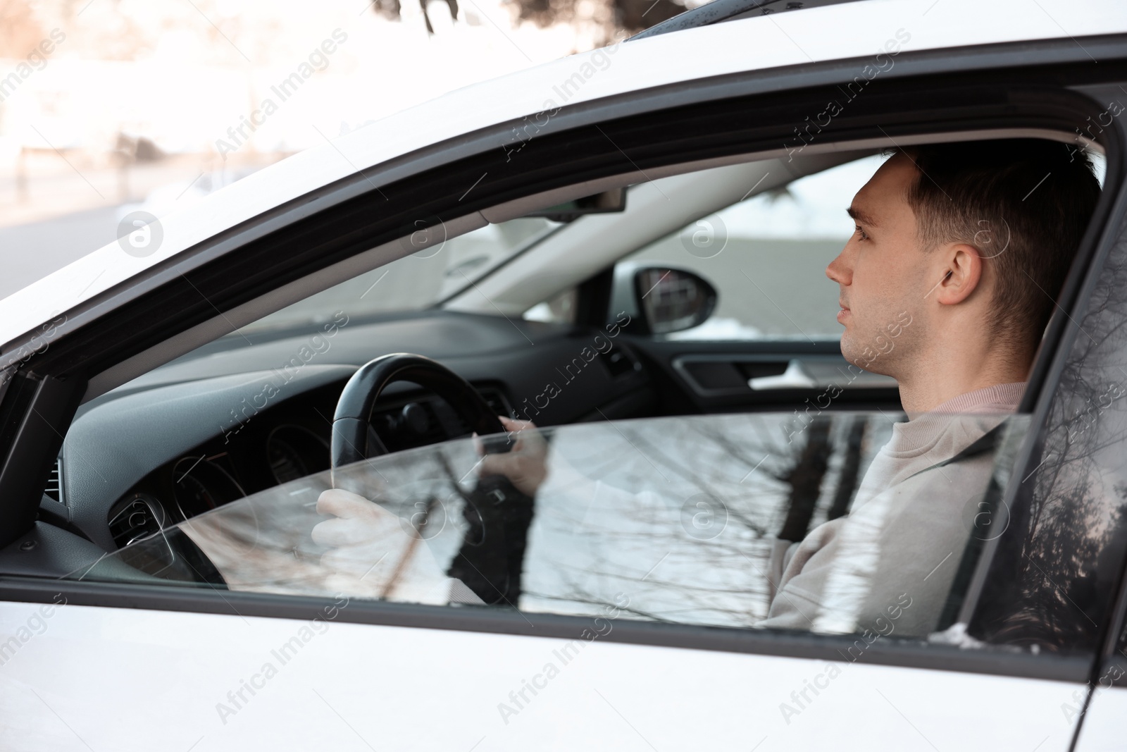 Photo of Driver behind steering wheel of modern car, view from outside