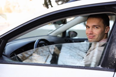 Photo of Driver behind steering wheel of modern car, view from outside