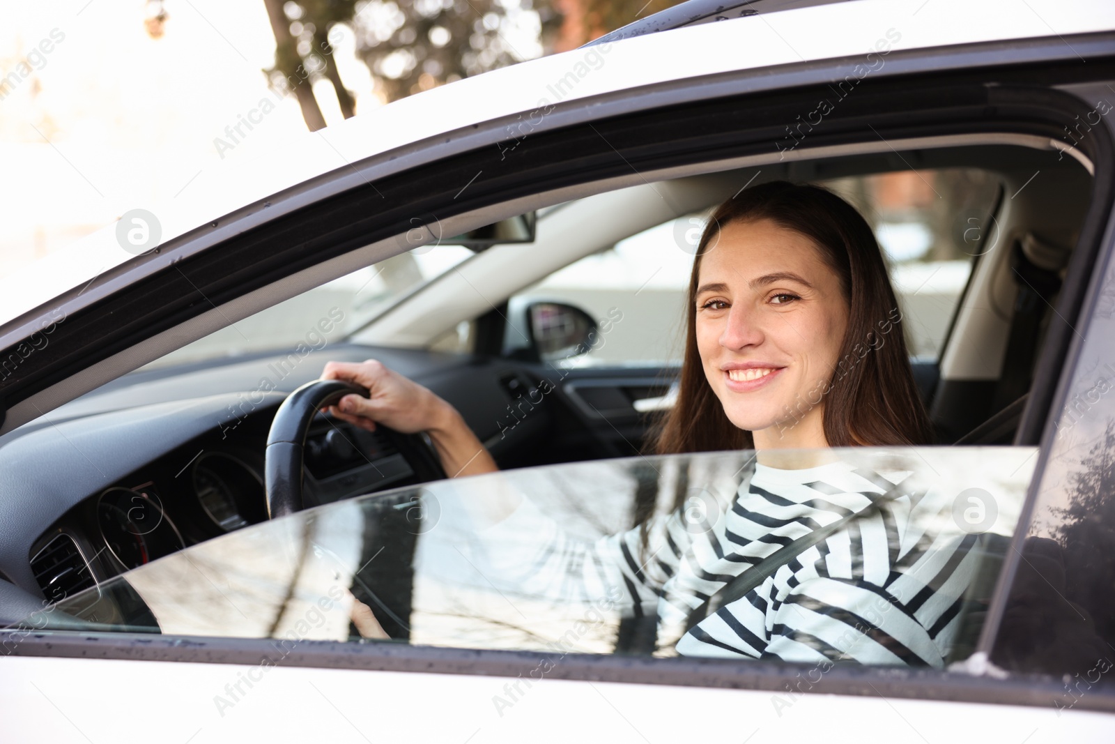 Photo of Driver behind steering wheel of modern car, view from outside