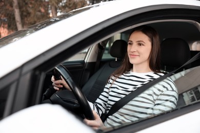 Photo of Driver behind steering wheel of modern car, view from outside