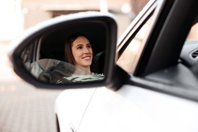 Photo of Driver driving modern auto, view through car side mirror